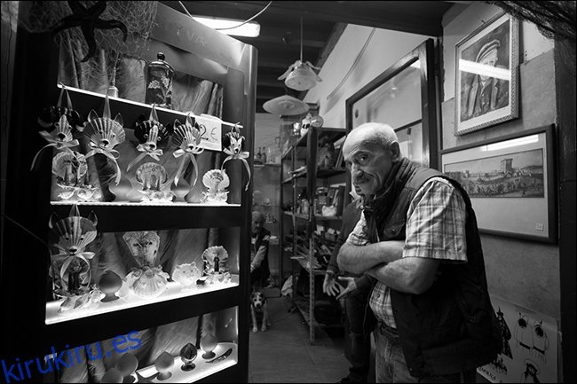 Anciano con los brazos cruzados en la tienda de curiosidades