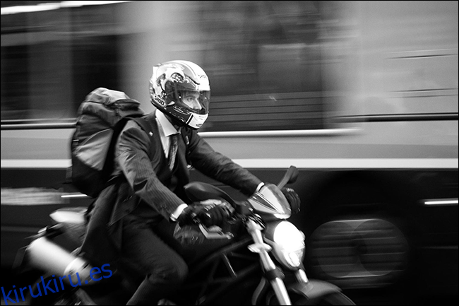 Hombre en traje de motocicleta con autobús borrosa moviéndose detrás de él
