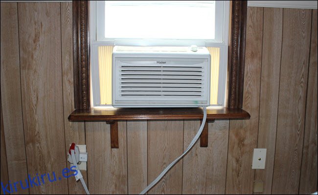 una unidad de aire acondicionado de ventana conectada a un enchufe inteligente, que está enchufado a un tomacorriente.