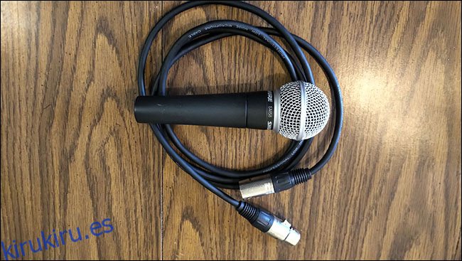 Un micrófono Shure SM58 encima de un cable XLR de AmazonBasics sobre una mesa.