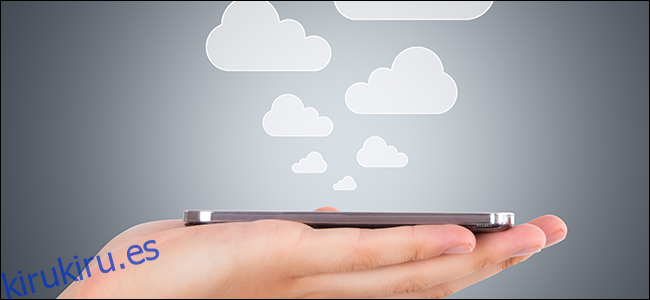 Una mano que sostiene un teléfono mientras las nubes se elevan, simbolizando archivos que se guardan en la nube.