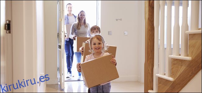 Una familia feliz llevando cajas a una casa.