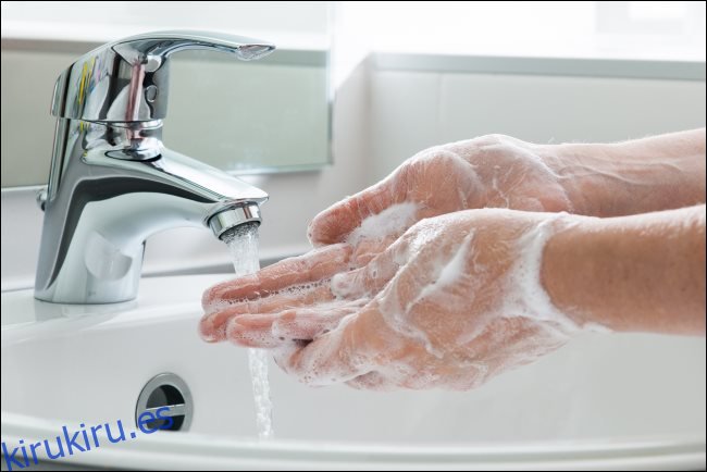 Lavarse las manos con jabón bajo el grifo de agua.