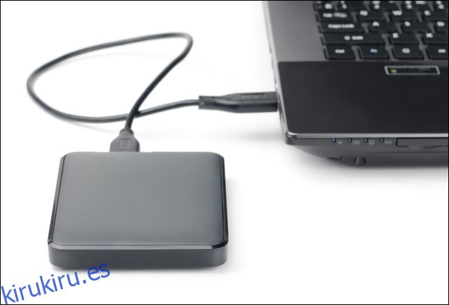Un disco duro externo conectado a una computadora portátil mediante un cable USB.