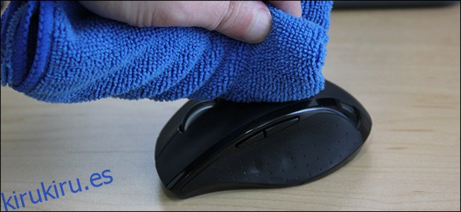 Una mano limpiando un mouse de computadora con un paño azul.