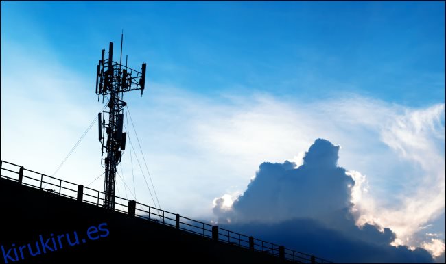 Una torre celular 5G contra un cielo azul con nubes blancas. 