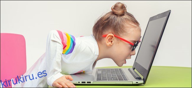 Niño con gafas apoyado en la computadora portátil