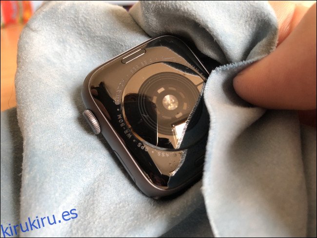 Una mano limpiando un Apple Watch con un paño.