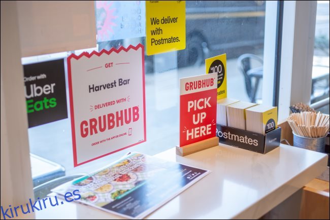 Letreros para GrubHub, Postmates y Uber Eats en un restaurante.