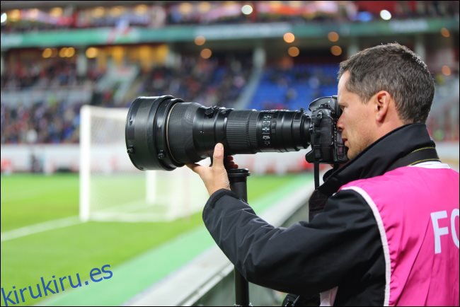 Un fotógrafo con un gran zoom óptico en un partido de fútbol.