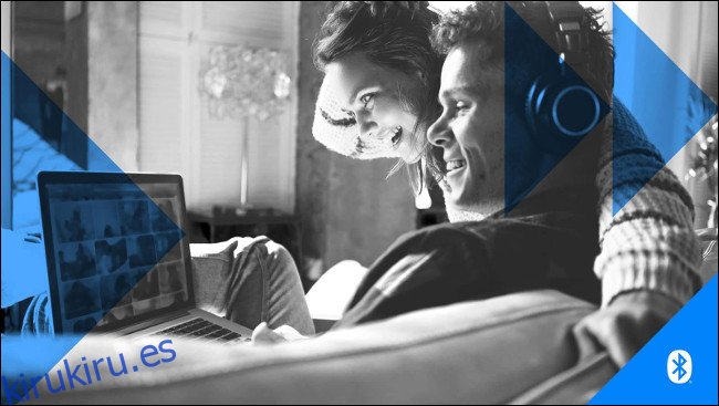 Un hombre y una mujer con audífonos mientras miran la pantalla de una computadora portátil.