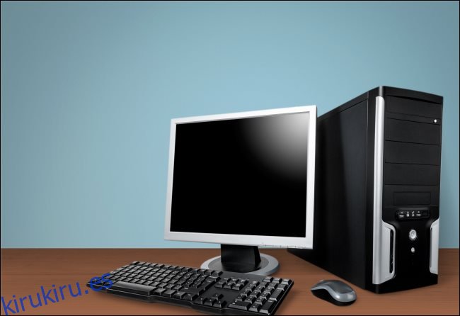 Una carcasa de PC de escritorio, un monitor, un teclado y un mouse sobre una mesa.