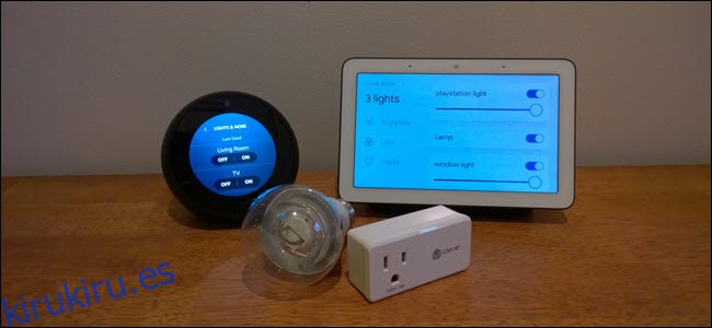 Un Echo Spot, Google Home, bombilla inteligente y enchufe inteligente sobre una superficie de madera.